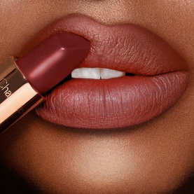 Charlotte Tilbury Matte Revolution Lipstick in deep berry-brown matte shade, shown applied to model's lips with gold-toned bullet visible