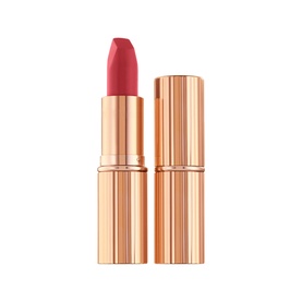 Charlotte Tilbury Matte Revolution Lipstick in a warm red-pink shade, rose-gold ribbed bullet case with matching cap removed