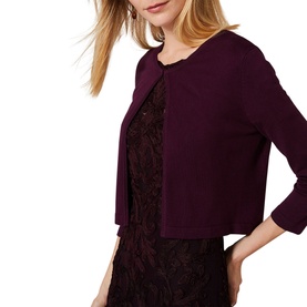 Model wearing Phase Eight Catie Cardigan in berry purple, cropped silhouette with three-quarter sleeves, styled over a lace dress