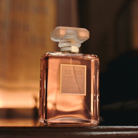 Chanel Coco Mademoiselle Eau De Parfum Spray in amber glass bottle with frosted square cap, warm golden lighting