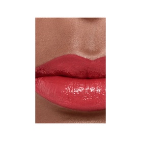 Model with CHANEL Ultrawear Shine Liquid Lip Colour in a coral-red shade, shown as a close-up lip swatch with glossy finish