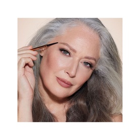 Model with Charlotte Tilbury Brow Cheat Brow Pencil in Taupe, applying to brows with precision tip applicator