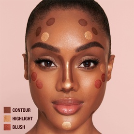 Model with Charlotte Tilbury Beauty Light Wand Highlighter in Medium/Deep shade, shown with contour and blush placement guide dots on face