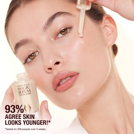 Model with Charlotte Tilbury Magic Serum Crystal Elixir dropper bottle held near glowing skin, with 93% agree skin looks younger claim overlay.