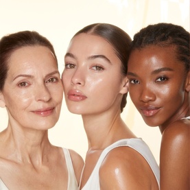 Three models with glowing, luminous skin showcasing Charlotte Tilbury Magic Serum Crystal Elixir results across different skin tones and ages.