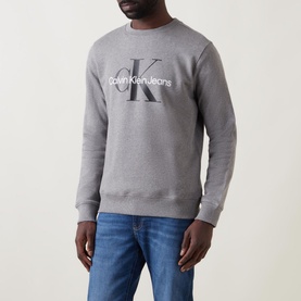 Model wearing Calvin Klein Jeans Monogram Logo Sweat Top in grey, with blue jeans visible below
