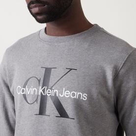 Model wearing Calvin Klein Jeans Monogram Logo Sweat Top in grey, with large CK monogram and logo print to chest