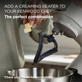 Kenwood Chef Flex Beater attachment shown fitted to a stand mixer, with a hand adding butter, demonstrating creaming capability.