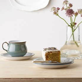 Denby Regency Green Tea/Coffee Cup and saucer on wooden surface, styled with a slice of cake and glass vase of wildflowers