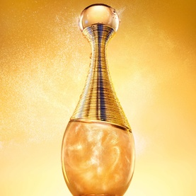 Dior J'adore Shimmering Hair Mist in gold ribbed bottle with shimmer spray effect against golden background