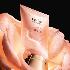 Dior Prestige La Mousse Micellaire Face Cleanser tube with foam, nestled within a soft pink rose bloom.