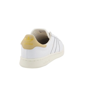 Adidas Earlham Trainers in white leather with yellow heel tab, three stripe detailing and cream sole, rear angle view