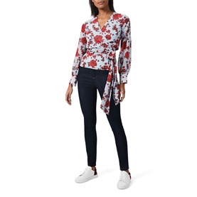 Model wearing Hobbs Elizabeth Blouse in multi red floral wrap style with long sleeves, styled with dark skinny jeans and white trainers