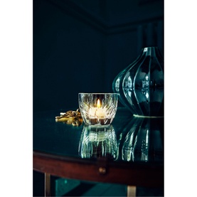 Waterford Enis Votive clear glass tealight holder with lit candle on dark wood table, styled with blue vase and gold ornament