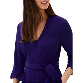 Model wearing Phase Eight Eydie Fluted Sleeve Jumpsuit in blue, showing V-neck, 3/4 fluted sleeves and belted waist detail