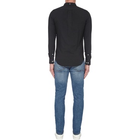 Model wearing Farah Vintage Brewer Slim Fit Shirt in black, long-sleeved with button cuffs, styled with blue denim jeans. Rear view
