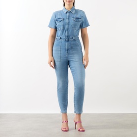 Model wearing Good American Fit For Success Denim Jumpsuit in blue with pointed collar, capped sleeves and utility chest pockets