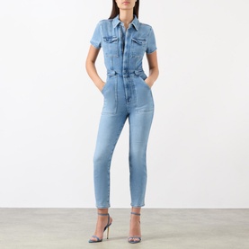 Model wearing Good American Fit For Success Denim Jumpsuit in blue with pointed collar, capped sleeves, utility chest pockets and straight leg
