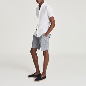 Model wearing Reiss Holiday Linen Slim Fit Shirt in white, styled with grey denim shorts and navy espadrilles