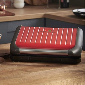 George Foreman Healthy Grill Red 7 Portion electric contact grill with red ribbed plates and grey base on wooden worktop