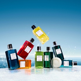 Herm&egrave;s Eau D'Orange Verte Moisturising Body Lotion displayed in a collection of colourful bath and body bottles and soaps on an icy surface