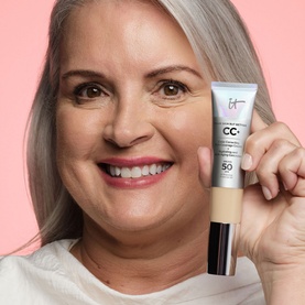 Model with IT COSMETICS Your Skin But Better CC+ Cream SPF 50+ in Light, held up beside face, wearing a white top