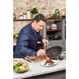 Jamie Oliver Cooks Classic Hard Anodised 26cm Sautepan in grey, used on kitchen counter with plated food and ingredients nearby
