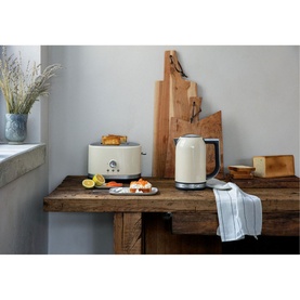 KitchenAid 1.7L Cream Kettle styled on a rustic wooden sideboard alongside a matching cream toaster and chopping boards