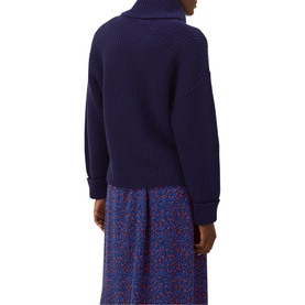 Model wearing Phase Eight Karine Chunky Roll Neck Sweater in blue, ribbed knit, shown from behind with floral midi skirt