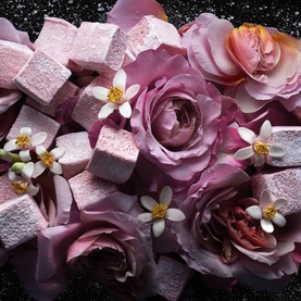 KILIAN PARIS Love, Don't Be Shy Refillable EDP lifestyle shot with pink marshmallows, roses and white orange blossom flowers