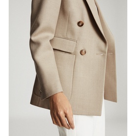 Model wearing Reiss Larsson Double Breasted Blazer in beige, close-up of button detail, styled with white trousers