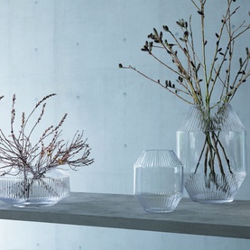 LSA Glassware Rotunda Wide 14cm Vase in clear ribbed glass, styled with two taller vases holding dried branches on a stone shelf