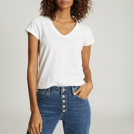 Model wearing Reiss Luana V-Neck T-Shirt in white, styled with blue button-fly jeans