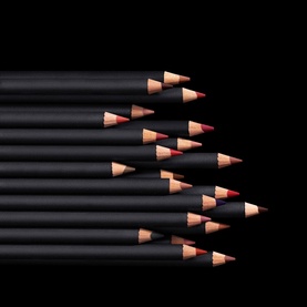 MAC Lip Pencil in Boldly Bare, multiple black barrel lip liner pencils fanned out showing nude-pink tips on dark background