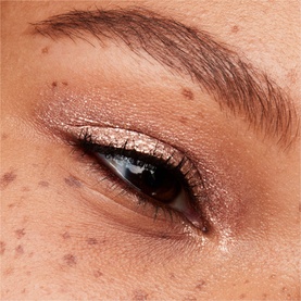 MAC Dazzleshadow Liquid eye shadow in Every Day Is Sunshine, a shimmering rose-gold shade, applied to lid with eyeliner on model's eye