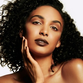 Model with MAC Studio Fix Sculpt and Shape Contour Palette in Medium Dark/Dark, wearing deep mauve lip colour, hand resting on cheek