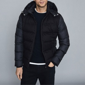 Model wearing Reiss Meyrim Padded Jacket in blue, styled with navy crew-neck jumper and dark jeans