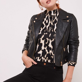 Model wearing Mint Velvet Maryland Skinny Jeans in black, styled with a black leather biker jacket and leopard print high-neck top