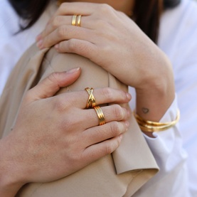 Model with Missoma Infinity 18kt Gold Vermeil Ring, gold-tone crossover design, styled with stacked gold rings and bangle