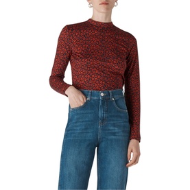 Model wearing Whistles Ikat Print Essential Top in red floral print, long sleeves, mock neck, styled with blue wide-leg jeans