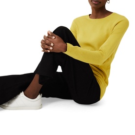 Model wearing Phase Eight Molla Crew Neck Sweater in yellow, styled with black wide-leg trousers and white trainers, seated pose