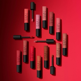 NARS Air Matte Lip Colour collection of mini lip gloss tubes in red and nude shades arranged on a red background