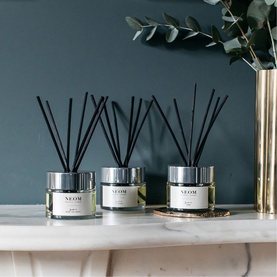 Neom Organics Perfect Night's Sleep Reed Diffusers styled on a marble shelf with black reeds, silver lids, and eucalyptus stems against a teal wall