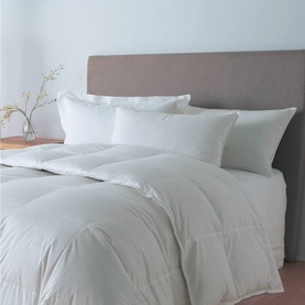 Nimbus Quilt Hungarian Goose Down Pillow Gold Collection in white, styled on a bed with matching duvet and grey upholstered headboard