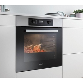 Miele Built In Large Capacity A+ Rated Single Oven in silver, installed in white kitchen cabinetry, shown roasting meat inside illuminated cavity