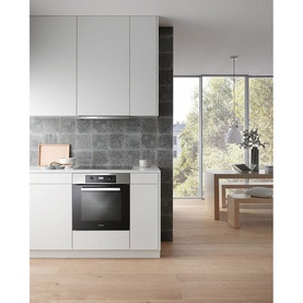 Miele Built In Large Capacity A+ Rated Single Oven in silver, installed in a modern white kitchen with grey stone splashback