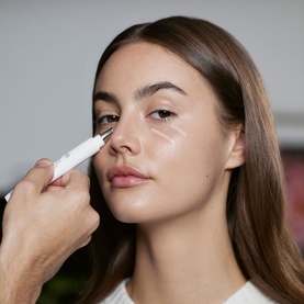 Model with SISLEY Phyto-Cernes Eclat Tinted Eye Concealer being applied under eye area with applicator tip, natural finish look