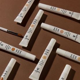 Sisley Phyto-Cernes Eclat Tinted Eye Concealer 15ml tubes and brush applicator arranged on brown background, multiple shades shown
