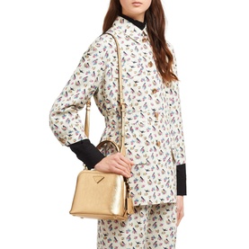 Model carrying Prada Accessories Matin&eacute;e Saffiano Leather Micro Bag in grey with gold hardware and adjustable shoulder strap