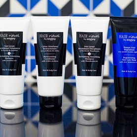 Sisley Hair Rituel haircare collection including Revitalising Smoothing Shampoo, conditioner and hair mask tubes on reflective surface